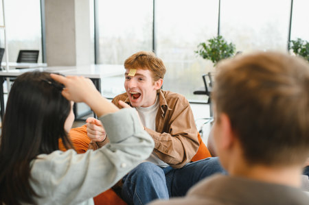 Cheerful colleagues enjoying a game of who am i during a break in a modern office environment,...