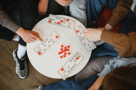 Friends enjoying a board game, placing red markers on numbered cards during a casual gathering