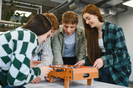 Four cheerful young startup colleagues enjoying a friendly game of table football during a break in their modern officeの写真素材