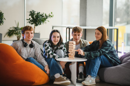 Four young students are sitting on beanbag chairs, enjoying their time together while playing a...