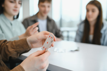 Group of friends enjoying leisure time together, playing cards and sharing laughter in a cozy home...