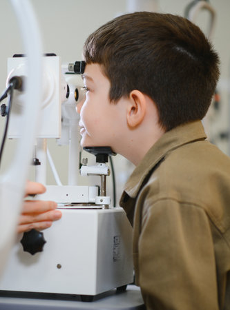 Ophthalmologist examining eyesight of young boy using a modern autorefractor in a medical clinic
