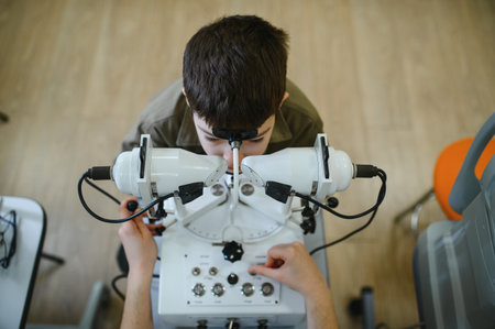Boy undergoing vision diagnostics with advanced equipment operated by ophthalmologist, highlighting...