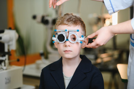 Boy undergoing vision testing with a trial frame during an ophthalmological examination in a clinic,...