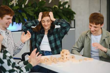 Group of young adults having fun playing wood block game, one girl getting stressed while playing...