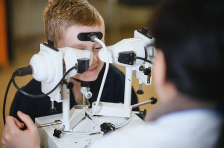 Young boy undergoing a vision check using advanced diagnostic equipment operated by an...