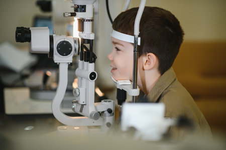 Smiling boy participating in a vision check using advanced ophthalmic equipment within a modern...