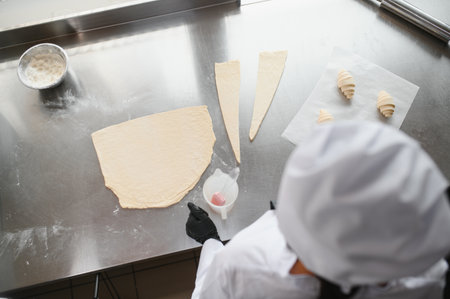 Baker skillfully working with dough, crafting fresh croissants in a bustling bakery kitchen,...