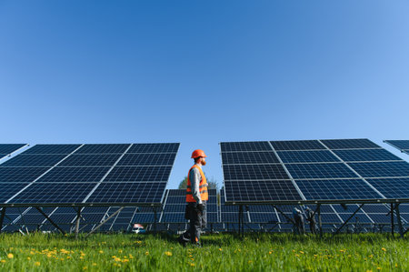 Engineer wearing safety helmet and vest walking and inspecting solar panels in a large solar power...