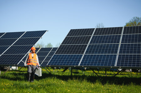 Engineer working at solar power station carrying toolbox walking near photovoltaic panels on a sunny...