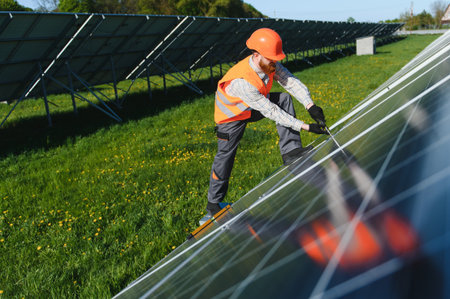 Solar panel technician meticulously installs and connects panels in a lush green field, contributing...
