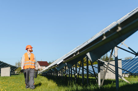 Male engineer carrying toolbox walking and inspecting solar panels in a solar power station,...