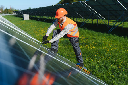 Technician working on photovoltaic panels in a large solar energy plant, tightening the screws with...