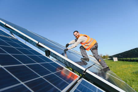 Engineer working on photovoltaic panels in a solar power plant, tightening bolts and ensuring...