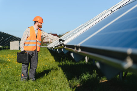 Engineer carrying toolbox checking operation of solar panels in a solar power station, concept of...