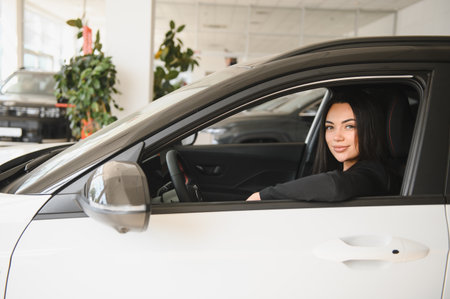 Customer sitting in the driver's seat of a new white car, smiling joyfully inside a modern car...