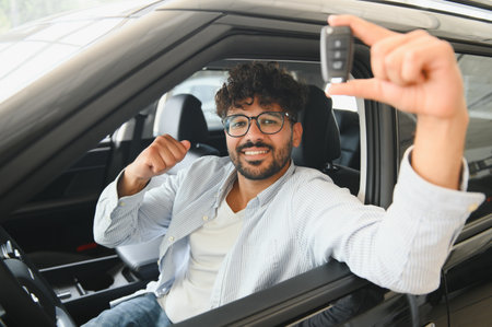 Excited customer showing car keys while sitting in his new vehicle, celebrating his purchase at the...