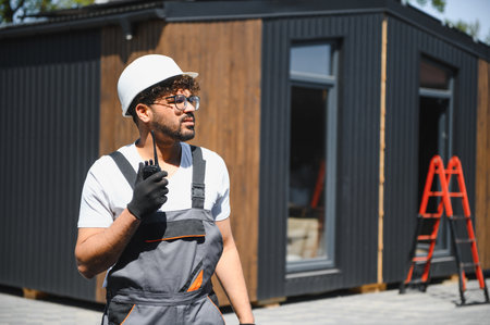 Construction worker using a walkie talkie, coordinating the lifting and transportation of a modular...