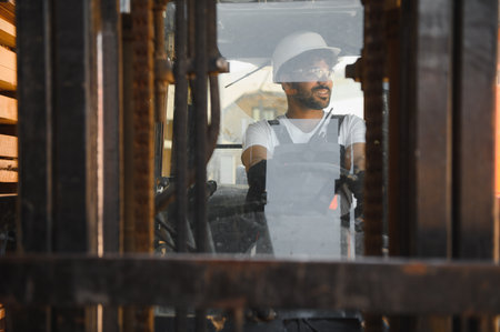 Arab warehouse worker wearing safety helmet driving forklift carrying lumber cargo, transporting...