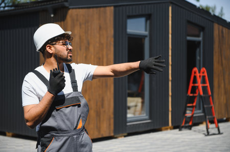 Construction worker using walkie talkie and giving instructions for placing prefabricated house...