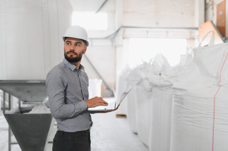 Industrial engineer wearing hardhat using laptop, managing aluminum and pvc windows and doors...