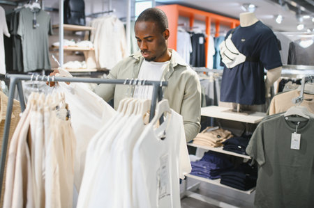 Customer through browsing clothing racks in a retail store, selecting a stylish white shirt while...