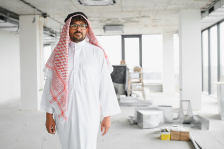 Arab businessman walking through construction site of new business center, overseeing progress and investmentの写真素材