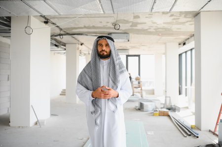 Arab businessman dressed in traditional clothing standing in a new business center during...