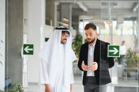 International operations manager explaining something to saudi business partner while walking in...