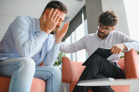 Male patient suffering from anxiety and depression having a psychotherapy session with professional...