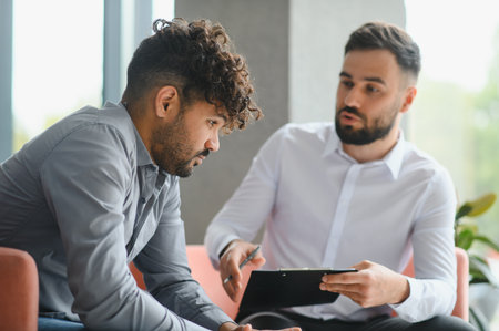 Psychologist presenting documents to a young Arab man during a therapy session, fostering open...