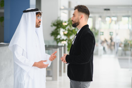 International operations manager meeting saudi business partner in traditional kandura, discussing...