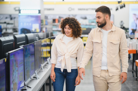 Young couple walking through a consumer electronics store, discussing options while selecting a new television for their home entertainmentの写真素材