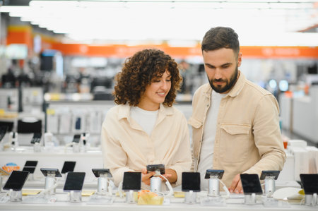 Young couple comparing and selecting new smartphones while browsing through the latest electronic...