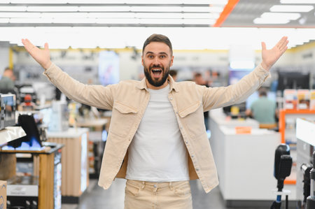Happy customer expressing joy with open arms after purchasing new home appliances in a large electronics storeの写真素材