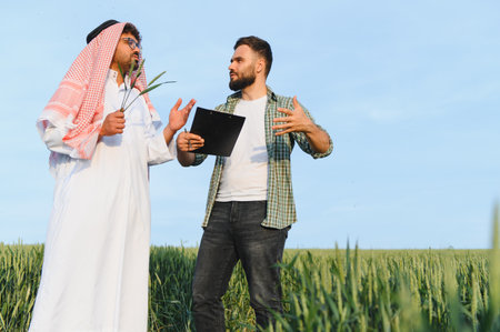 Arab businessman and a farmer engaging in a discussion about the current state of their wheat field,...