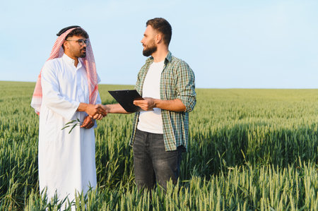 Arab businessman and a farmer shaking hands in a wheat field, symbolizing a successful agribusiness...