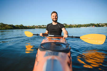 Man paddling a kayak on a river, enjoying water sports and active recreation under the warm sun on a...