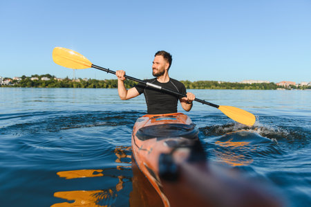 Man paddles an orange kayak on a lake or river, enjoying the sunshine and practicing water sports
