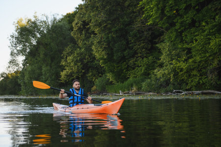 Man kayaking on a serene lake, surrounded by lush greenery and tranquil nature, enjoying a peaceful...
