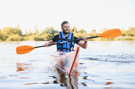 Man with life jacket paddling kayak on lake, enjoying water sports and active recreation in natureの写真素材