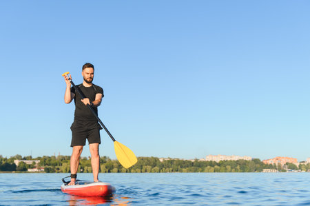 Young sportsman is paddling, balancing on a sup board on a lake, enjoying watersports in summer