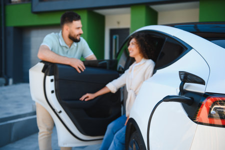 Happy couple charging their electric vehicle at their modern home, showing their commitment to eco friendly transportation and a sustainable lifestyleの写真素材