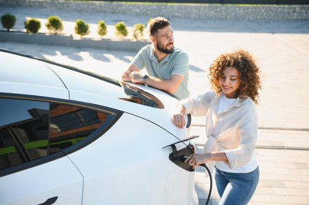Young couple charging their electric vehicle at their house, demonstrating commitment to eco friendly transportation and renewable energyの写真素材