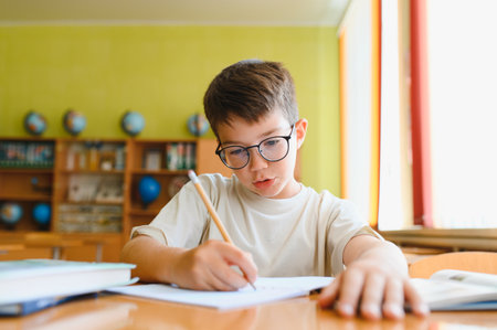 Young student writing diligently in a notebook with a pencil, focused on completing homework...
