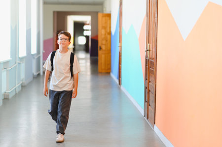 Confident young student walking in colorful school hallway, enjoying break time and navigating through the educational environmentの写真素材