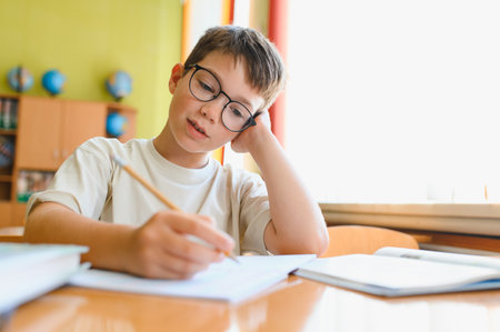 Young student writing diligently in a notebook, focusing intently on studies while seated at a desk...