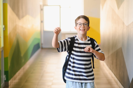 Smiling student walking happily down a colorful school hallway after class, carrying a backpack and enjoying a carefree moment of joyの写真素材