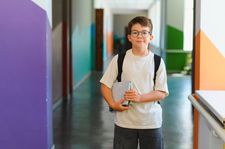 Portrait of a cheerful student carrying books, navigating a vibrant school corridor, ready for learning and academic successの写真素材