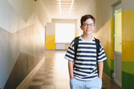 Portrait of a cheerful schoolboy standing in the school hallway, ready to embrace the day and eager to learnの写真素材